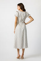 Back view of a woman wearing a polka dot dress on a white background