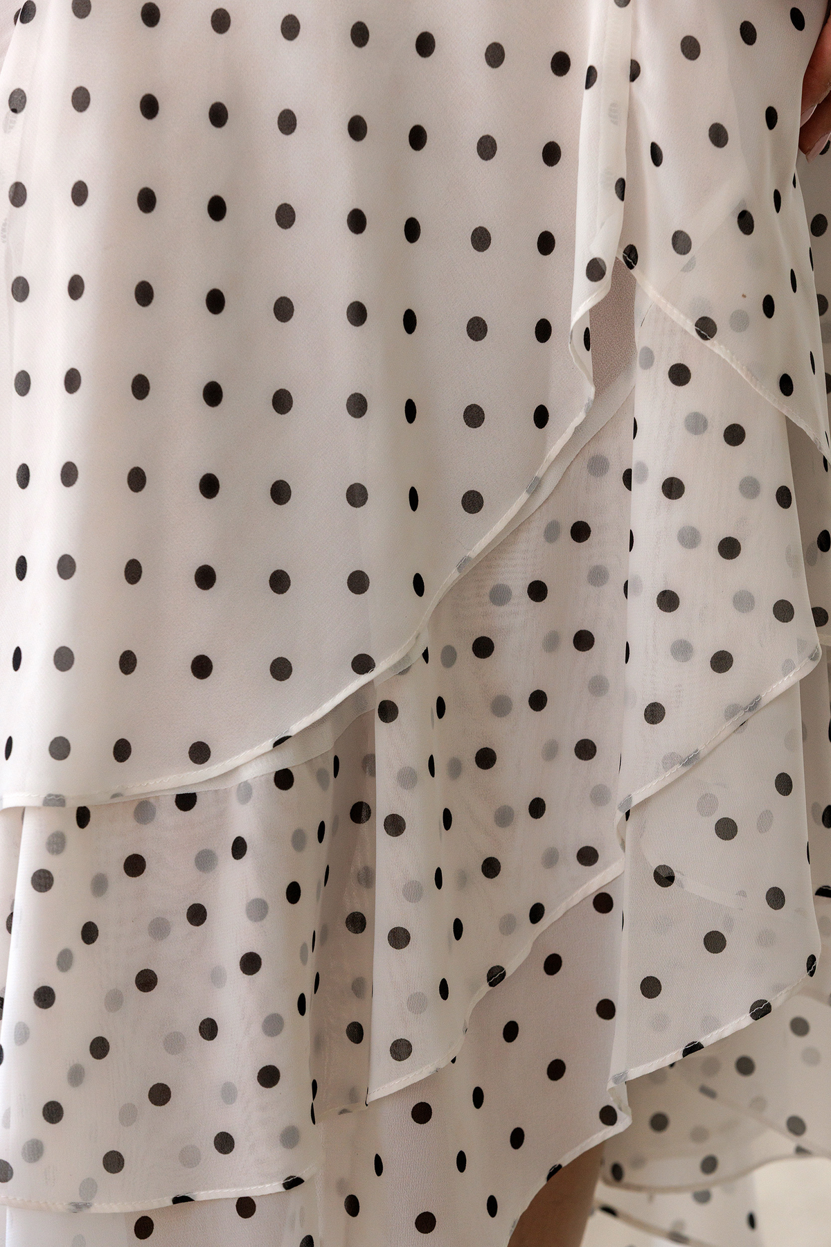 Polka dot dress with ruffled layers on a neutral background