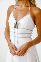 A person wearing a white dress with blue accents on a white background