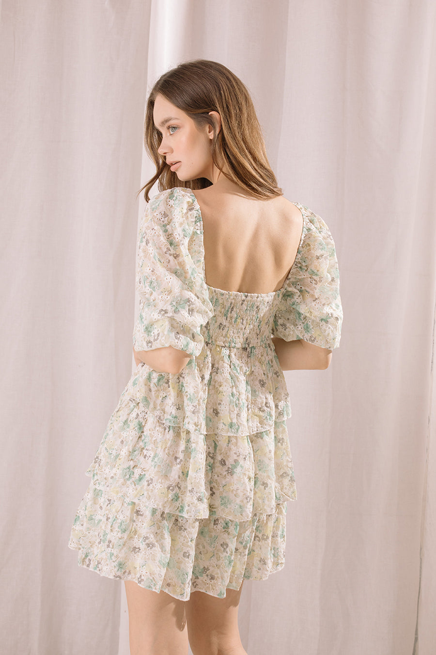 Woman wearing a floral dress with a backless design against a plain background