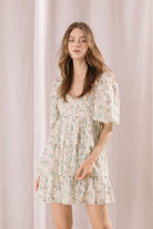 Woman wearing a floral mini dress against a plain background