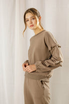 Woman wearing a brown outfit against a plain background