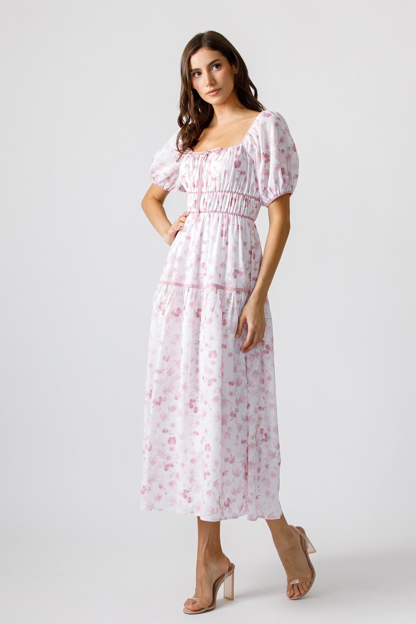 Woman wearing a white dress with pink floral pattern on a white background