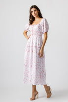Woman wearing a white dress with pink floral pattern on a white background