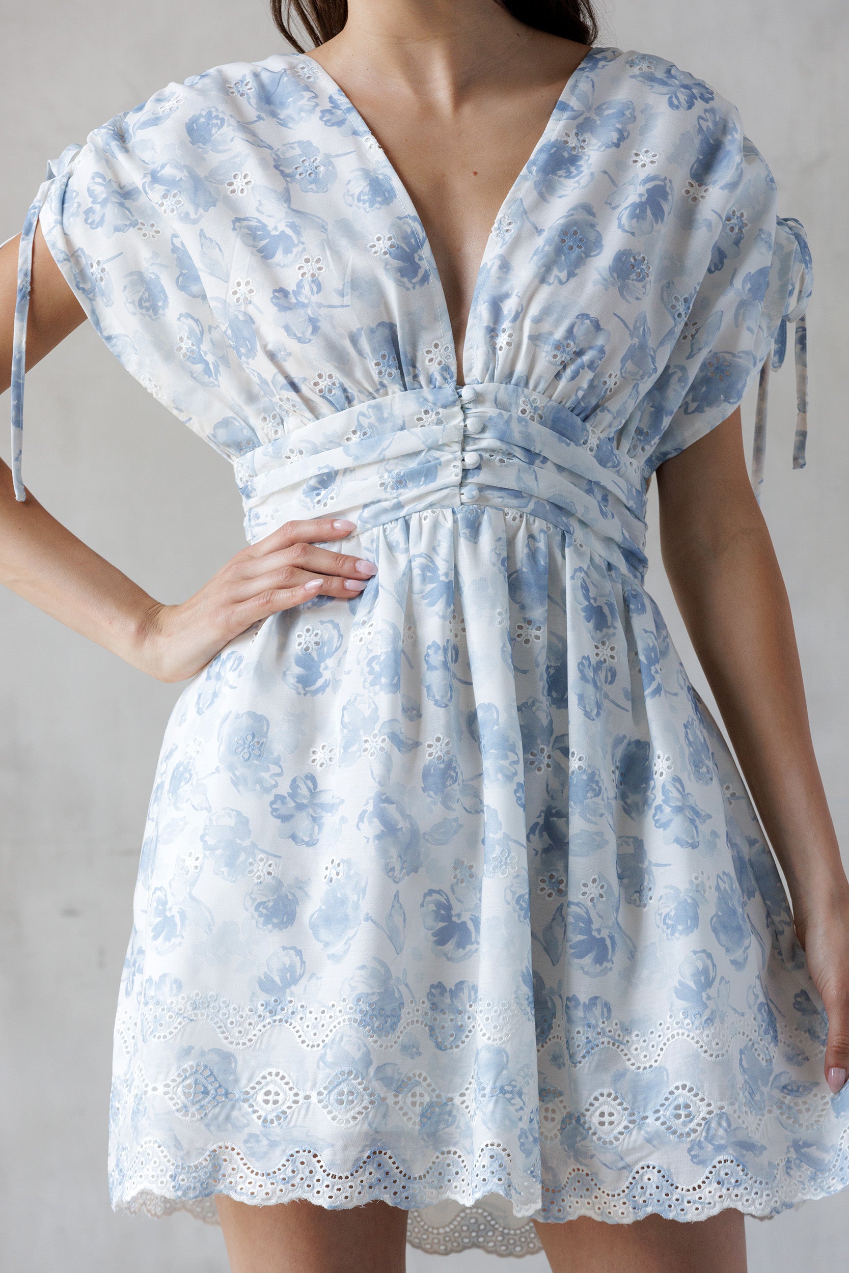 Blue and white dress with blue floral pattern worn by a person on a plain background