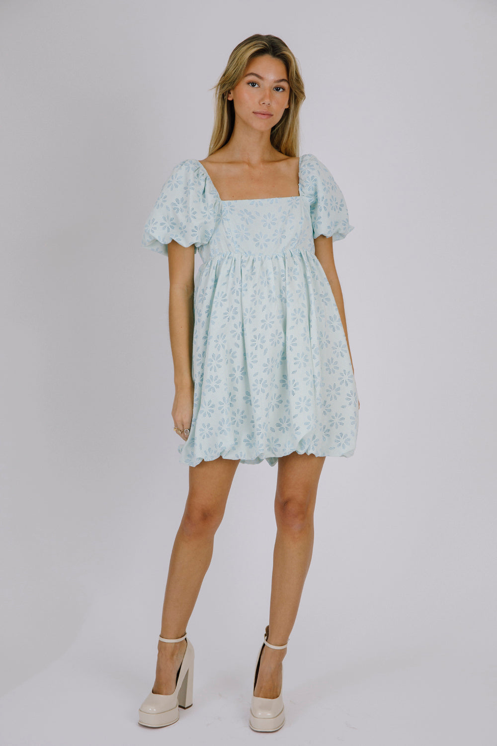 Woman wearing a light blue floral dress on a white background