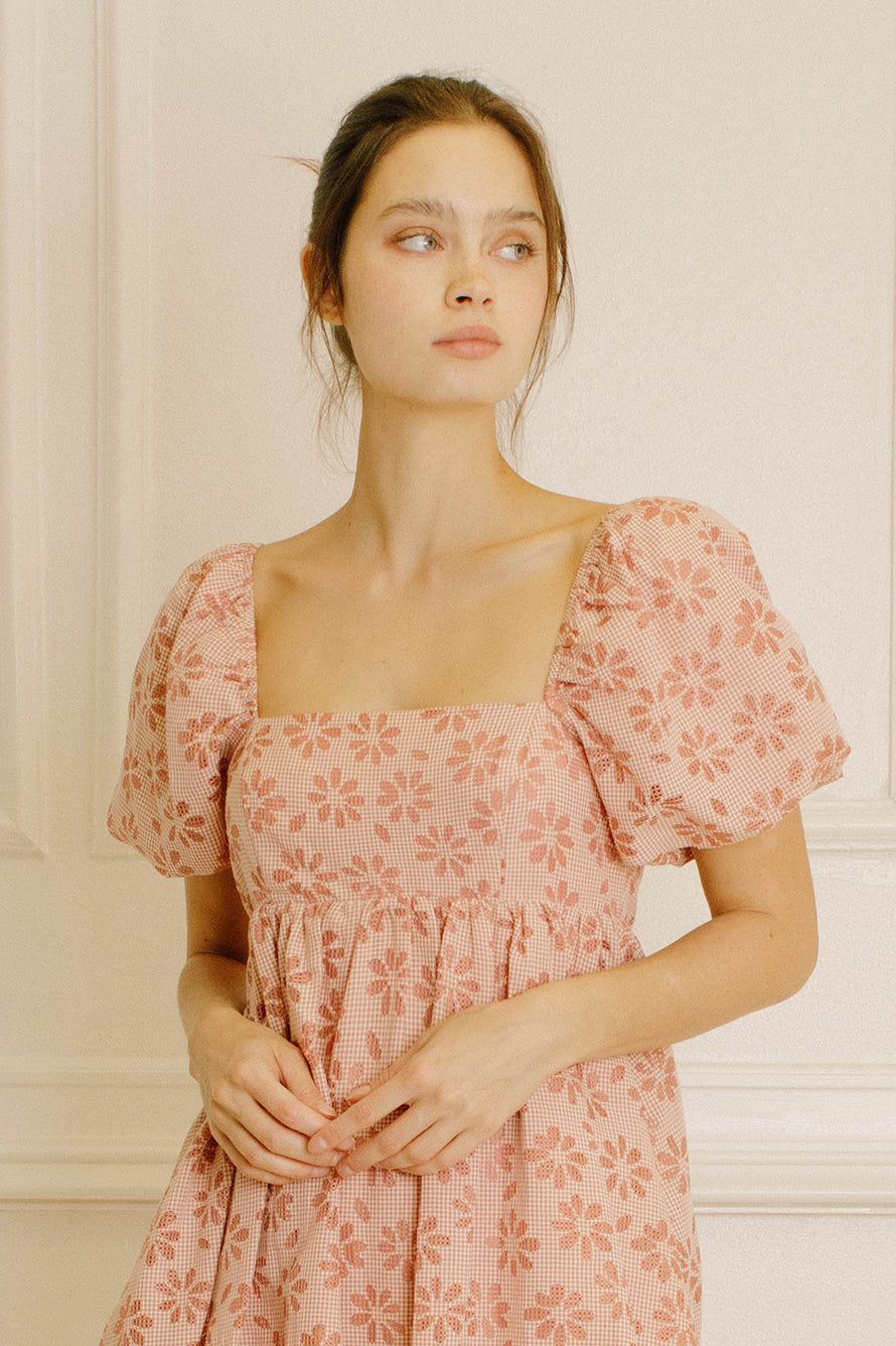 Woman wearing a pink gingham mini dress against a neutral background