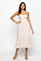 Woman wearing a strapless cream floral dress on a white background