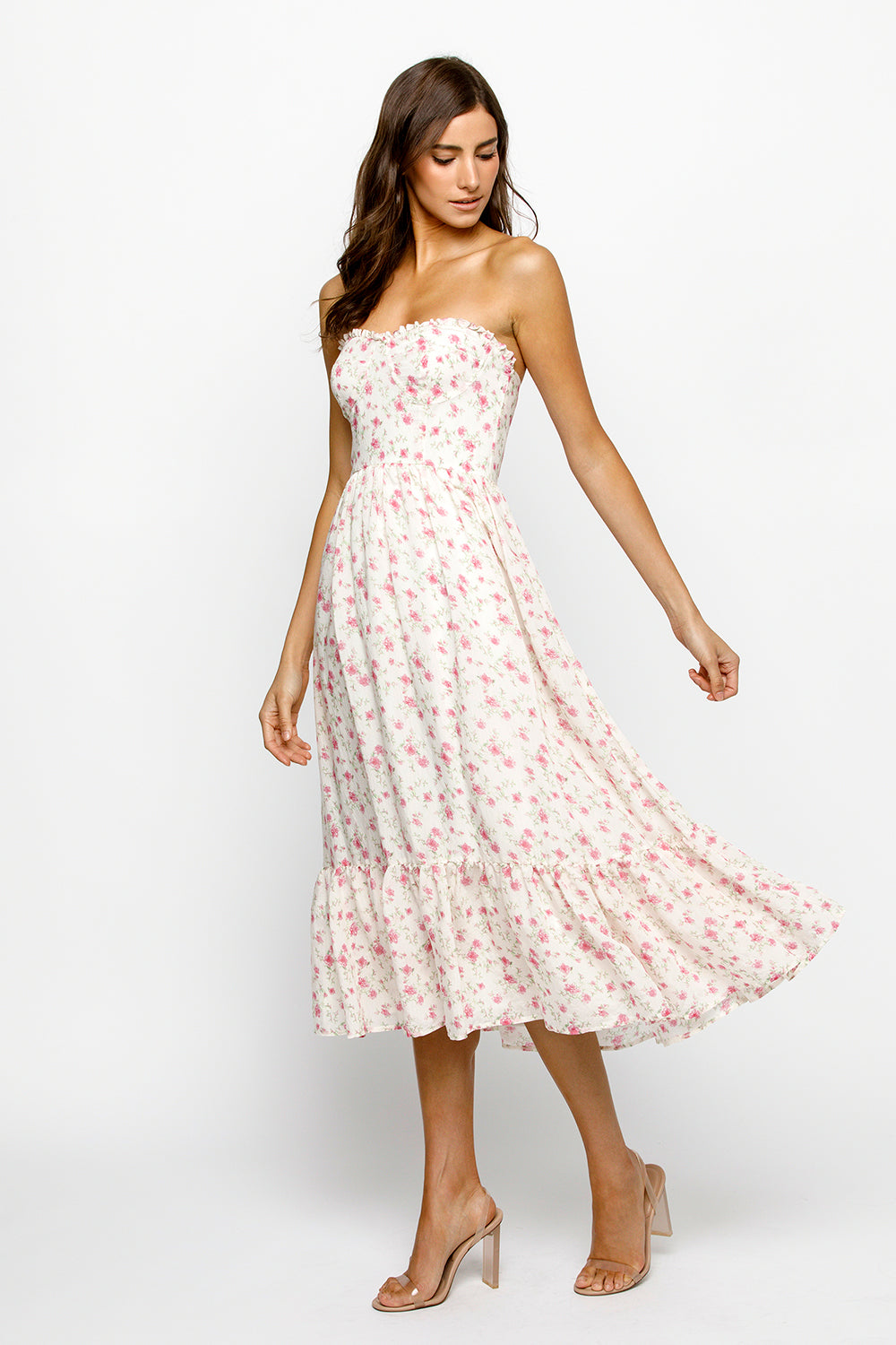 Side view of a woman wearing a strapless cream floral dress on a white background