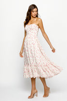 Side view of a woman wearing a strapless cream floral dress on a white background