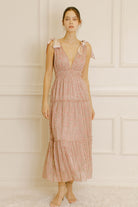 Woman wearing a pink metallic floral dress against a neutral wall.