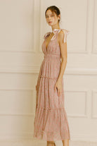 Side view of a woman wearing a pink metallic floral dress against a neutral wall.