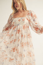 Close-up view of a beige floral dress with long sleeves on a plain background