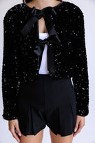 Black sequin top with two bows and black shorts on a white background