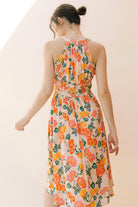 Back view of a woman wearing a floral dress on a plain background