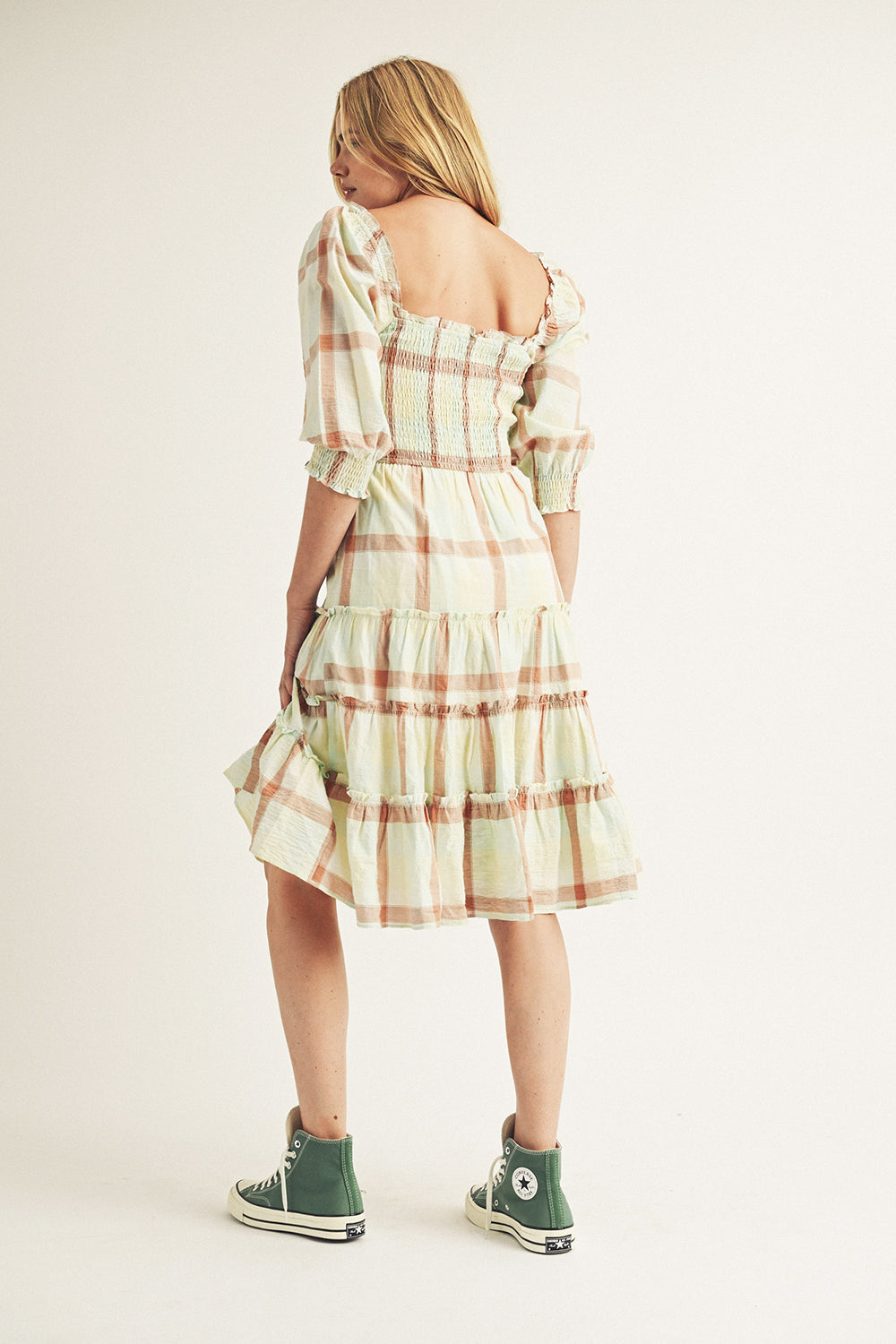 Woman wearing a plaid dress with a neutral background