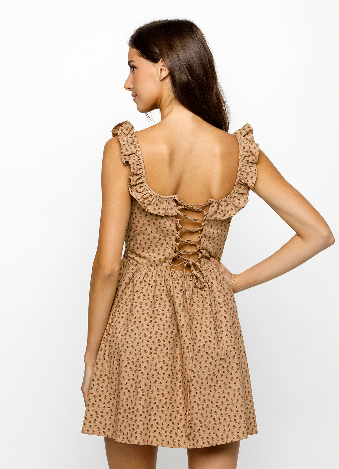Woman wearing a brown and red floral dress with ruffled straps on a white background