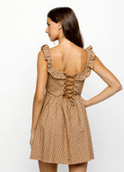Woman wearing a brown and red floral dress with ruffled straps on a white background