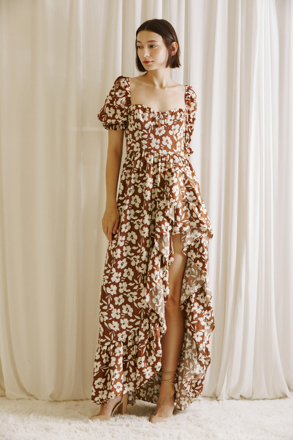 Woman wearing a brown and white floral dress with a side slit