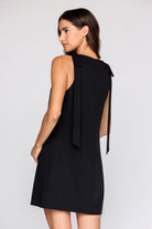 Back a of a woman wearing a black sleeveless dress on a white background