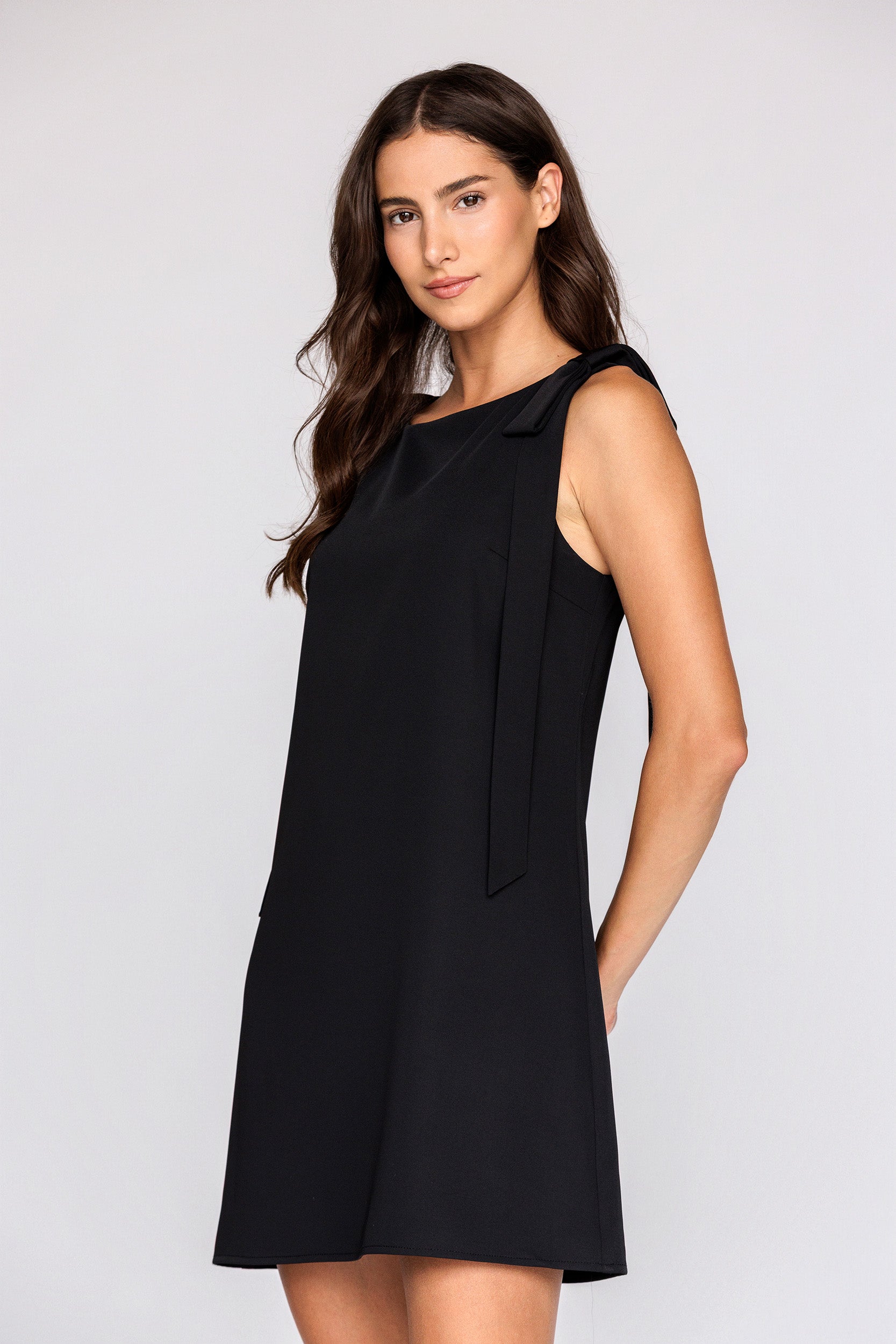 Woman wearing a black sleeveless dress against a white background