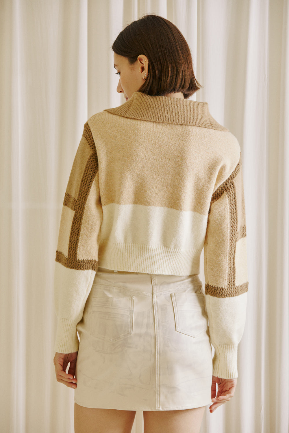  Back view of a woman wearing a brown and beige color block sweater