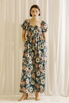 Woman wearing a flowy jumpsuit standing in front of white curtains
