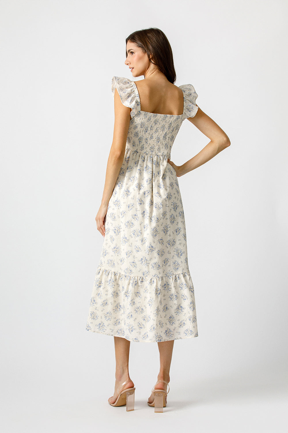 Woman wearing a cream floral dress on a white background