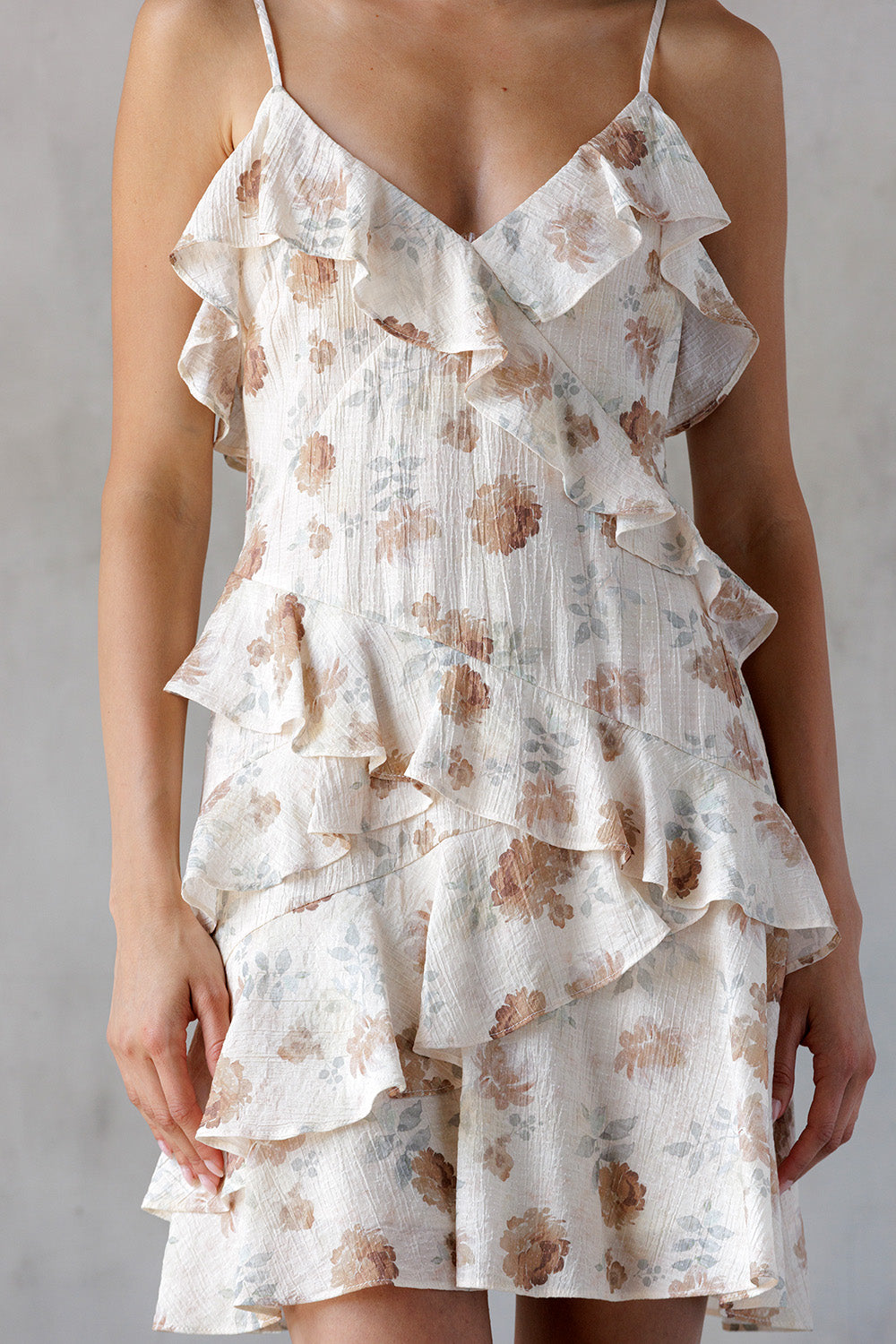 Beige and brown floral tiered dress with ruffles on a plain background