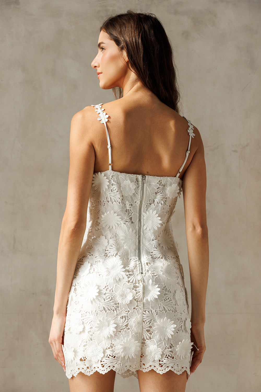 Woman wearing a white lace dress against a neutral background