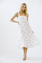 Woman wearing a white dress with a subtle pattern on a white background