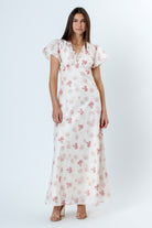 Woman wearing a white floral dress with flutter sleeves on a white background