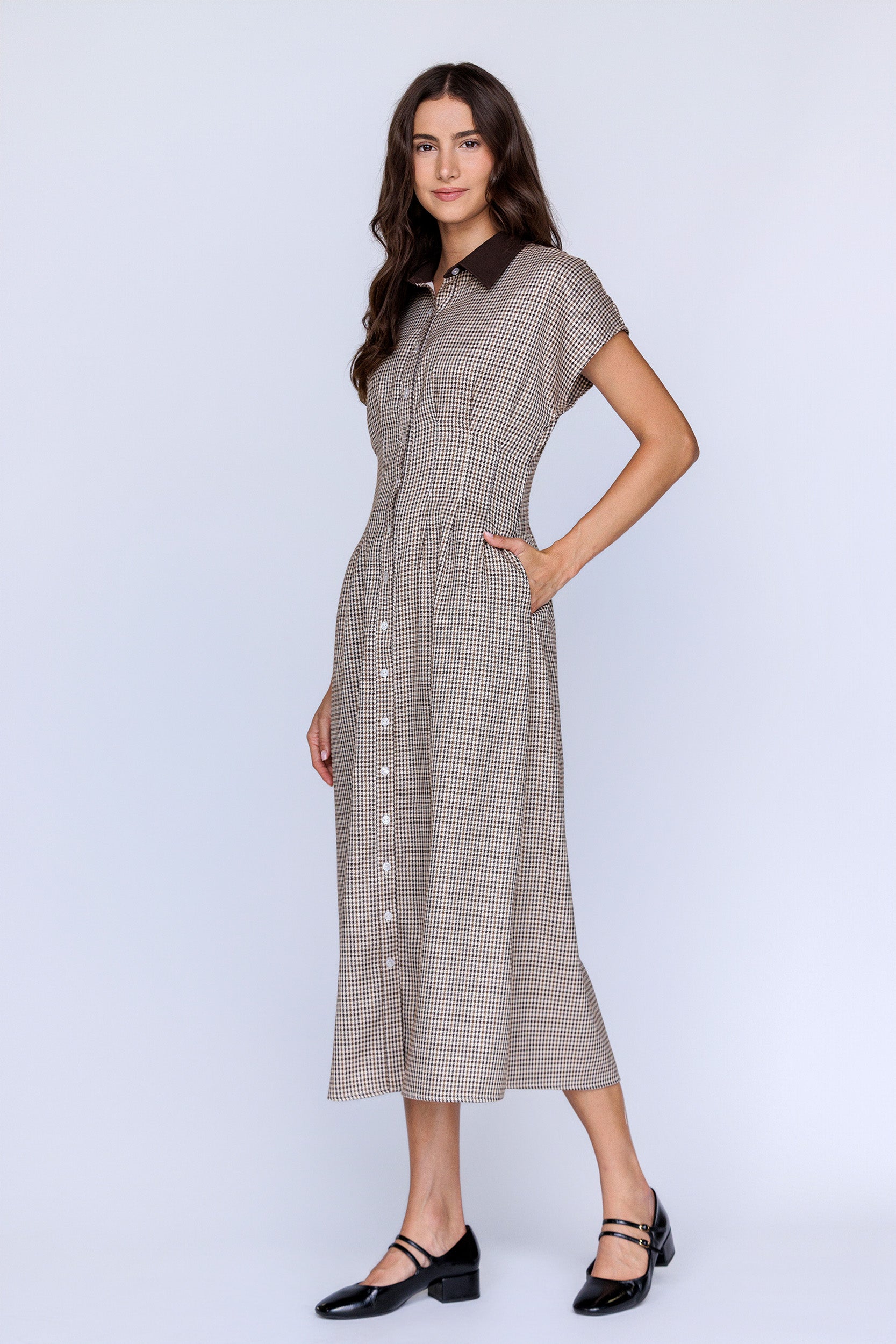 Side view of a woman wearing a checkered dress on a white background