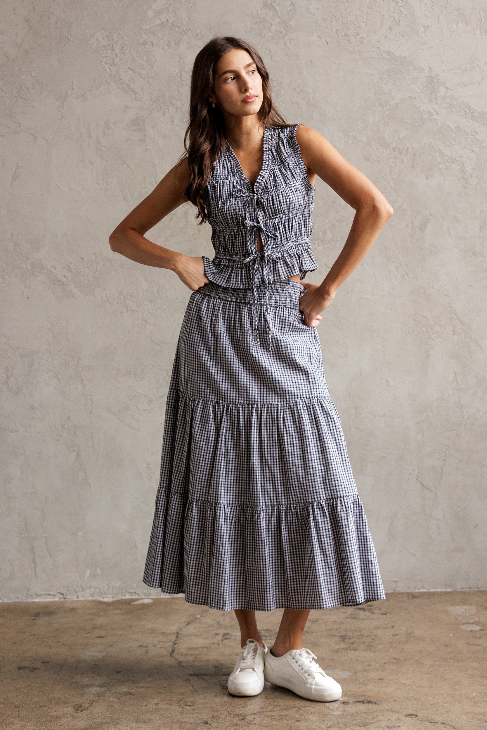 Woman wearing a blue checkered set of top and a skirt against a neutral background
