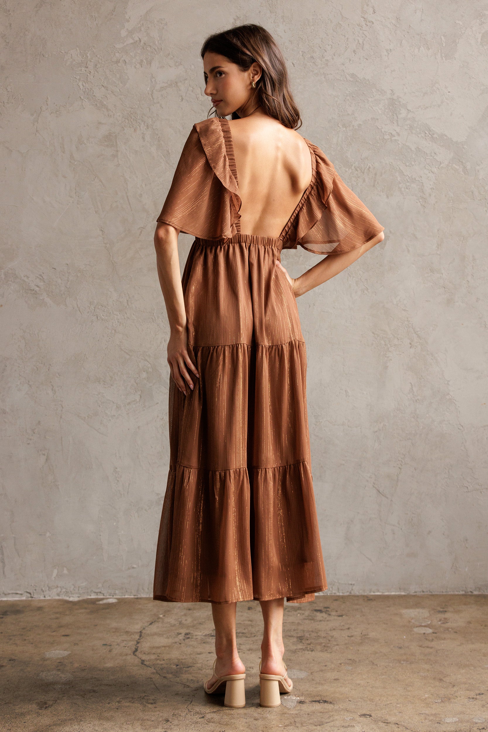 Woman wearing a brown dress against a plain wall