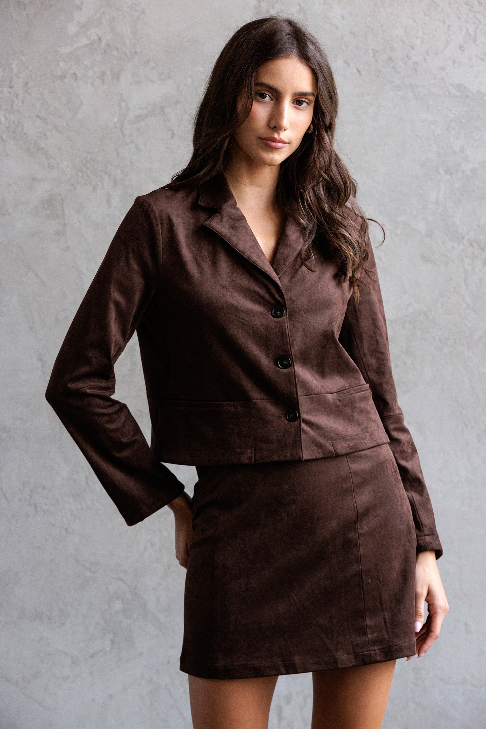 Woman wearing a brown suit against a gray background