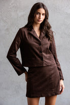 Woman wearing a brown suit against a gray background