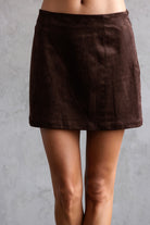 Brown suede skirt worn by a person on a gray background