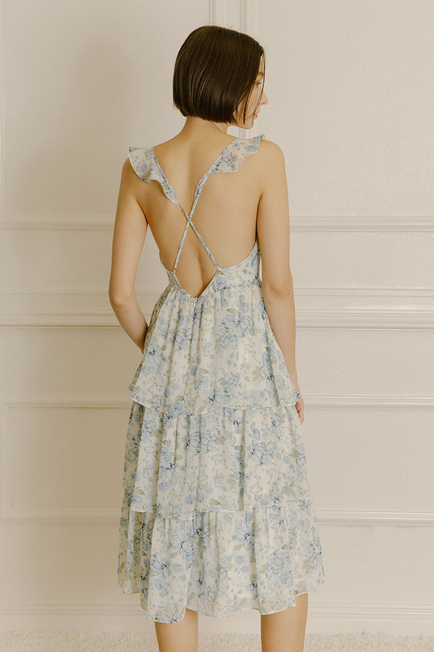 Back view of a woman wearing a blue floral midi dress with adjustable cross-back spaghetti straps