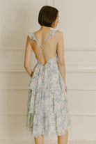 Back view of a woman wearing a blue floral midi dress with adjustable cross-back spaghetti straps