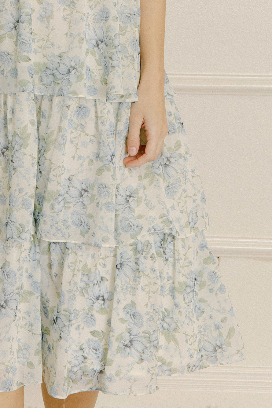Woman wearing a blue floral dress with a ruffled tiered bottom