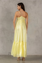 Back of a woman wearing a yellow dress against a gray concrete wall