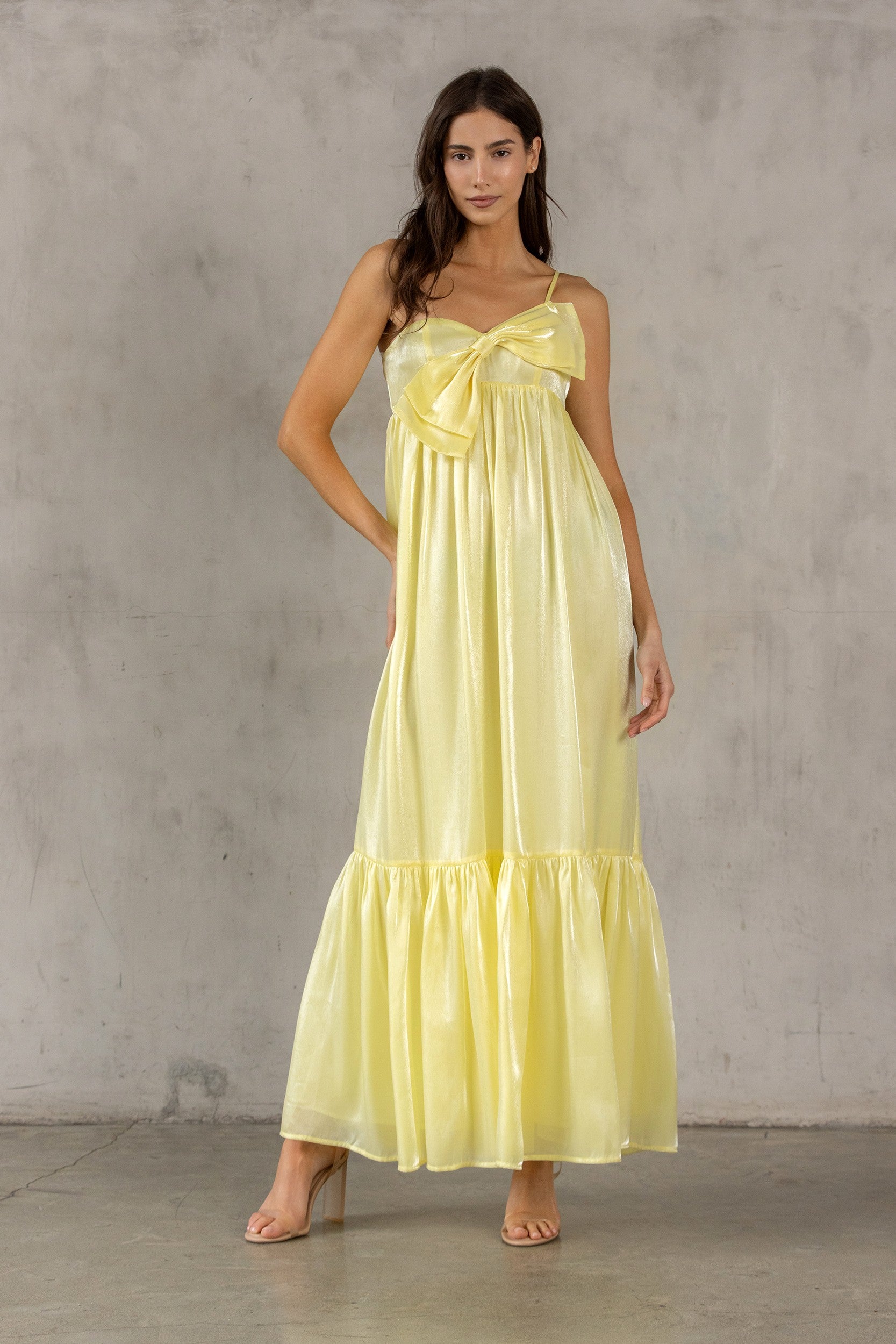 Woman wearing a yellow dress against a gray concrete wall.