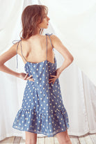 Back view of a woman wearing a blue floral dress against a white background