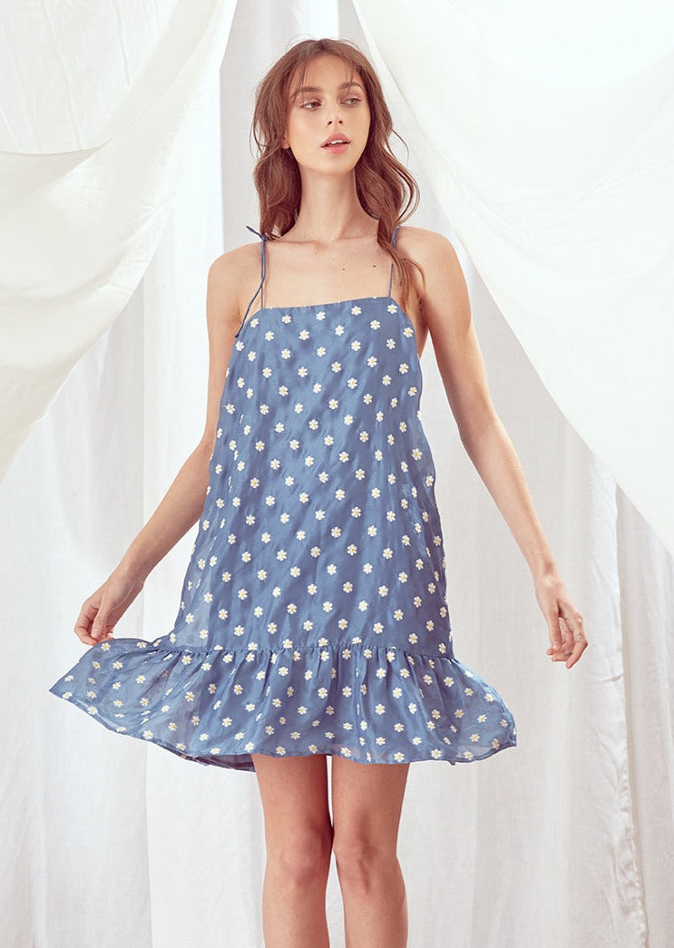 Woman wearing a blue floral dress against a white background