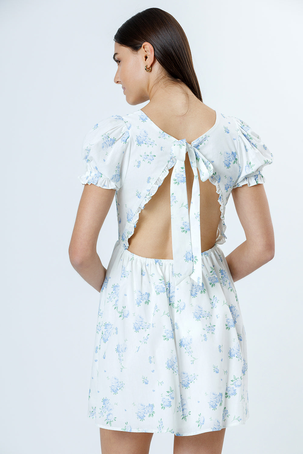 Woman wearing a floral dress with an open back on a white background