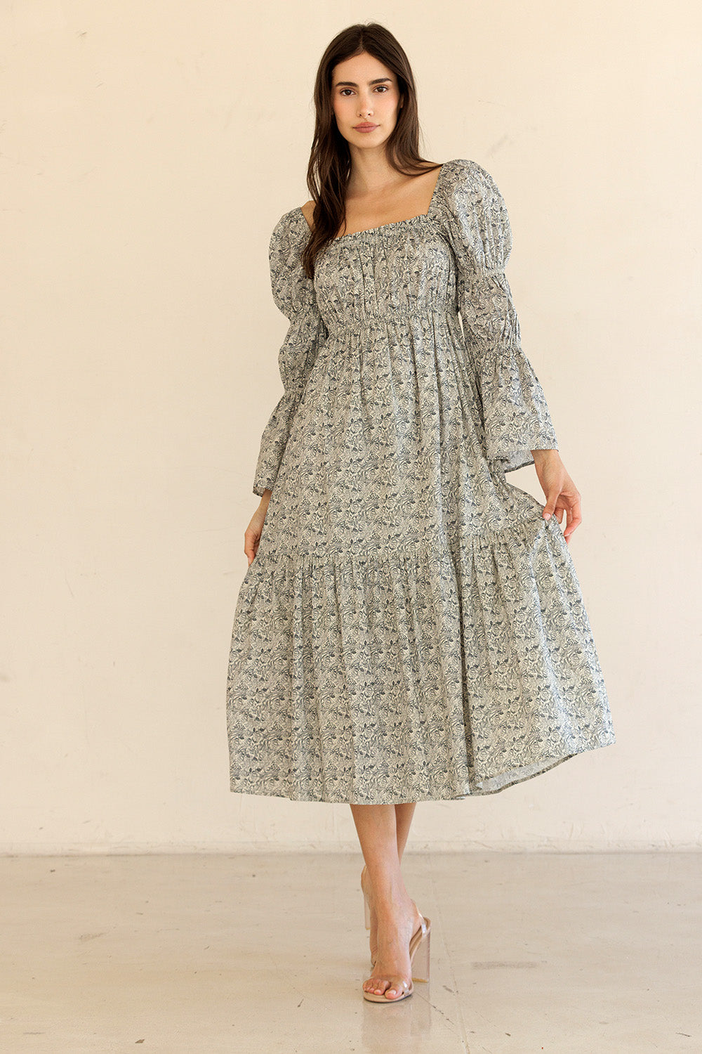 Woman wearing a floral midi dress with long sleeves against a plain background