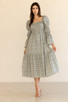 Woman wearing a floral midi dress with long sleeves against a plain background