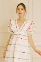 White dress with colorful stripes against a beige wall.