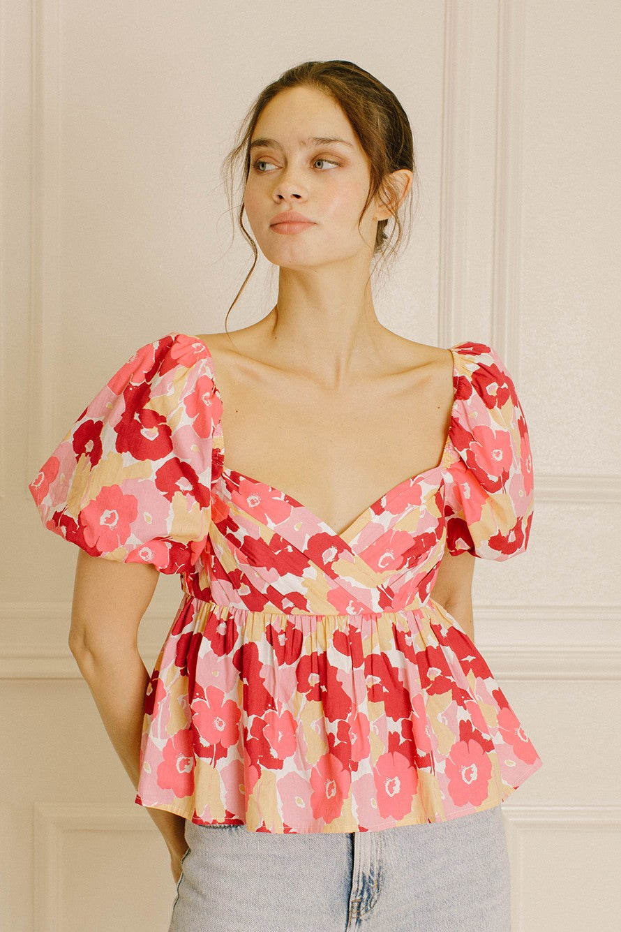Woman wearing a pink floral top with a neutral background
